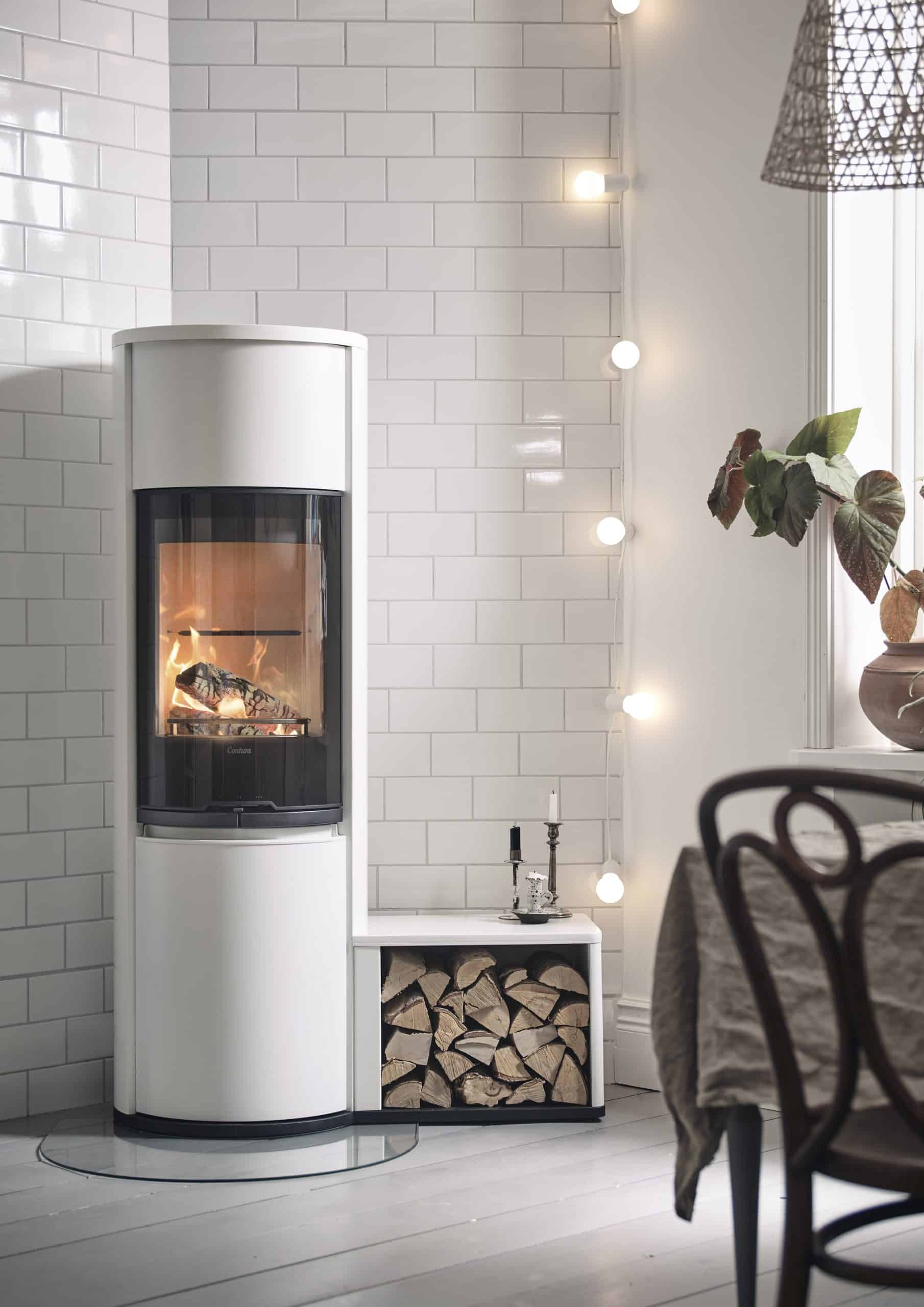 flamme dans poêle à bois 690G Contura blanc haut avec accumulateurs de chaleur et bûcher blanc accolé rempli de bûches refendues de bois